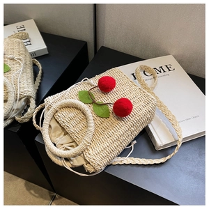 Detail of woven straw bag with handmade red cherry pompoms and drawstring lining