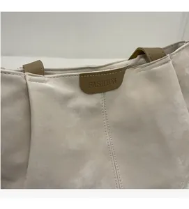 Detail of tote bag with marble texture, brown handles and a Fashion leather label