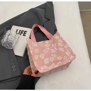 Close-up of pink tote bag showing 3D white floral texture and gold snap button