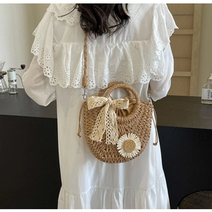 Detail view of woven straw bag featuring a large lace bow and a white daisy applique