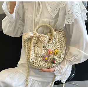 Detail of straw woven bag with 3D daisies, lace bow, and drawstring cotton lining