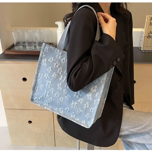 Detail of light blue tote bag with 3D floral texture and thick webbing handles