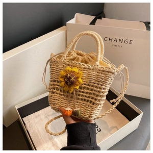 Detail of straw bucket bag featuring sunflower charm and drawstring fabric lining
