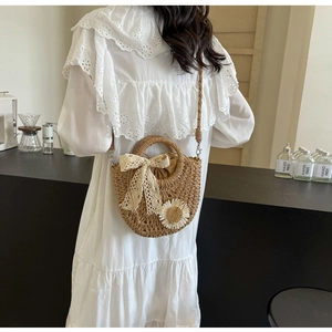 Handmade woven straw bag featuring a lace bow and daisy charm decoration