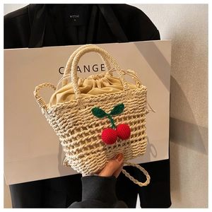 Detail of hand-woven straw bag with red crochet cherry charms and drawstring lining