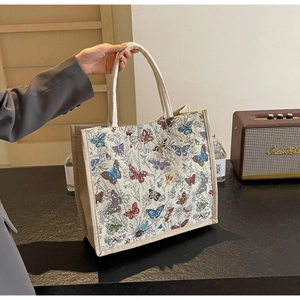Détail du sac cabas tissé avec broderies papillon colorées et poignées renforcées