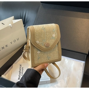 Gros plan détaillé du sac à bandoulière en paille beige avec broderie florale et cuir