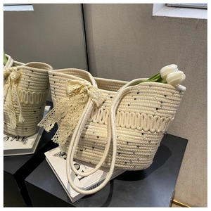 Détail d'un sac cabas tissé crème avec un nœud en dentelle et une texture en corde de coton