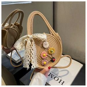 Detail einer runden Strohtasche mit weißer Spitzenschleife und bunter Sonnenblume