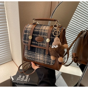 Detail des Karo-Leder-Rucksacks mit Goldring-Griff und Plüsch-Monster-Anhänger-Dekoration