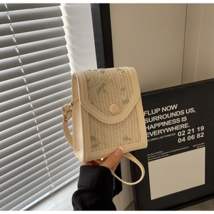 Détail du sac bandoulière en paille crème avec broderies florales vertes et métal doré