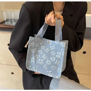 Detail of light blue 3D floral jacquard tote with gold buckle and canvas straps
