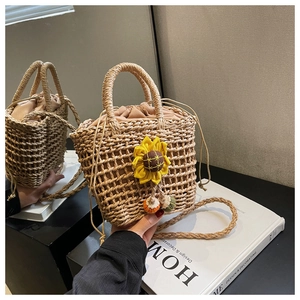 Detail of handwoven straw bucket bag with a yellow sunflower charm and drawstring liner