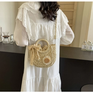 Detail of handmade woven straw bag with white daisy pattern and lace bow detail
