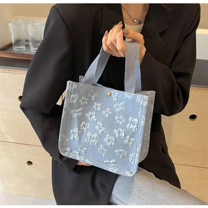 Close-up of light blue canvas tote bag with floral texture and gold snap button closure