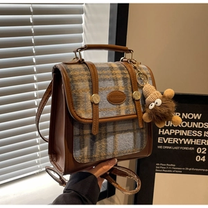 Detail eines karierten Rucksacks im britischen Stil mit brauner Schnalle und Igel-Anhänger