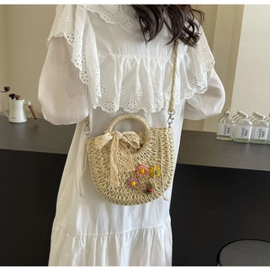 Detail of woven straw handbag with colorful floral appliques and lace bow on a white dress