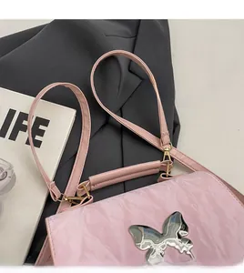 Détail d'un sac rose clair en cuir froissé avec une boucle papillon en métal argenté
