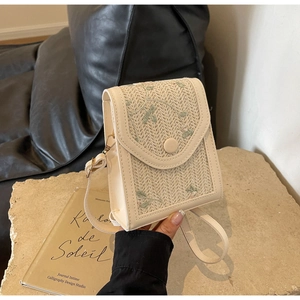 Détail du sac bandoulière crème avec tissage en paille et broderies florales vertes