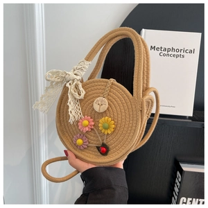 Detail einer runden Strohtasche mit Blumen und Spitzenschleife im Bücherregal