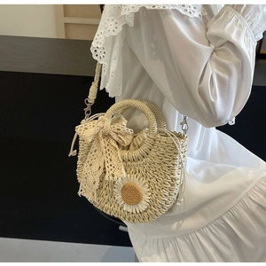 Close-up of beige handmade straw woven handbag with lace bow and daisy floral detail