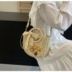 Detailed macro view of woven straw texture with lace bow and floral accents on bag