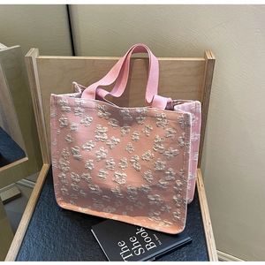 Detail of pink canvas tote bag featuring 3D floral texture on a wooden shelf