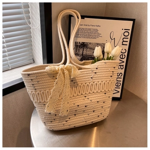 Détail du sac de plage tissé crème avec nœud en dentelle et texture mouchetée