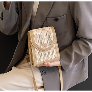 Macro view of woven straw crossbody bag with khaki leather trim and textured pattern