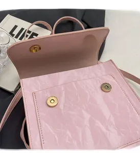 Détail du sac à main rose brillant avec fermoir magnétique doré et texture plissée