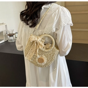 Straw handbag with white daisies, lace bow, and drawstring closure worn with a white dress