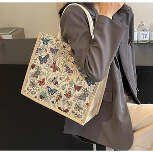 Détail du jacquard papillon coloré sur cabas crème avec poignée corde porté par mannequin