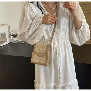 Modèle portant un sac bandoulière en paille tressée avec broderies et bords cuir