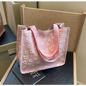 Detail of pink canvas tote bag with 3D white floral texture on wooden display