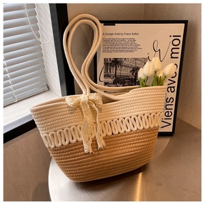 Détail du sac cabas tissé bicolore avec un nœud en dentelle blanche et motif à vagues