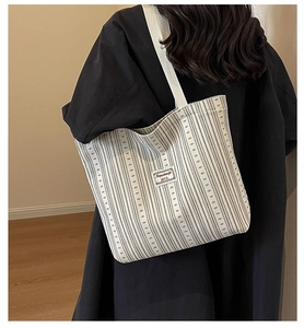 Detail of striped corduroy tote bag with wide strap and minimalist woven label