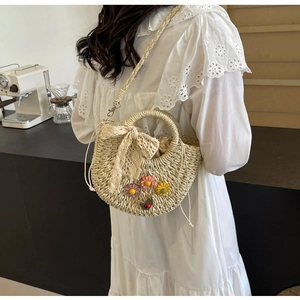 Detail of handmade woven straw bag with floral accents and a lace bow charm