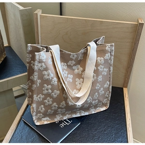 Close-up of khaki canvas tote bag with white floral embroidery and sturdy webbing handles