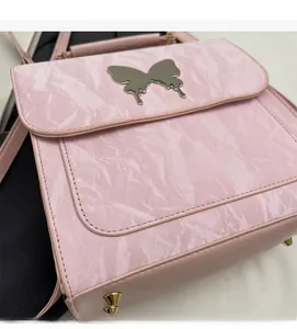 Détail du sac à dos rose avec texture marbre et décoration de papillon en métal doré