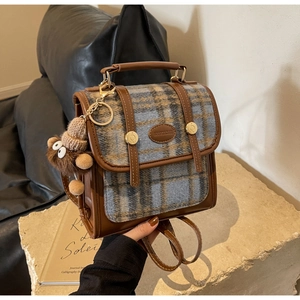 Detail eines karierten Rucksacks mit Lederschnallen und einem süßen Bären-Plüschanhänger