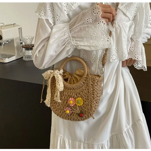 Detail of straw woven bag with colorful floral accents and elegant lace bow charm