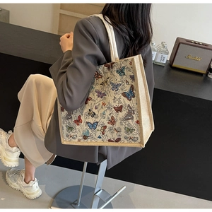 Grand sac cabas avec broderies papillons colorés et texture en toile porté à l'épaule