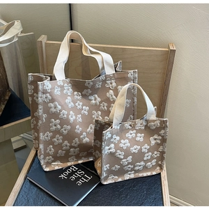 Close-up of khaki canvas tote bags with white embossed floral clover patterns