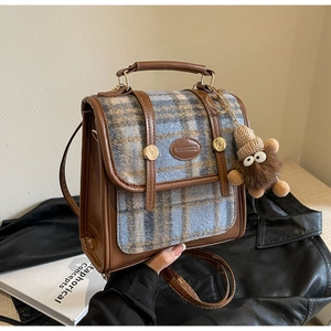 Detail der braunen Vintage-Ledertasche mit Plaid-Tweed-Einsatz und Plüschanhänger