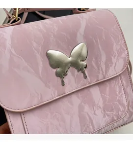 Gros plan d'un sac à main rose en cuir texturé avec boucle en forme de papillon argenté