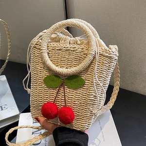 Handwoven straw bucket bag with red cherry accents and adjustable shoulder strap