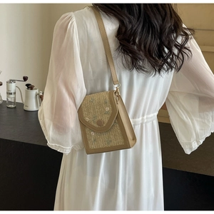 Détail d'un sac de téléphone en paille tissée avec broderie florale et bandoulière