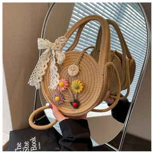 Detail der runden Strohtasche mit Spitzenschleife, Webblumen und Holzknopf-Deko
