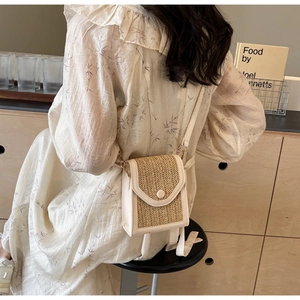 Detail of hand-woven cream crossbody bag styled with a floral dress in a cozy home setting