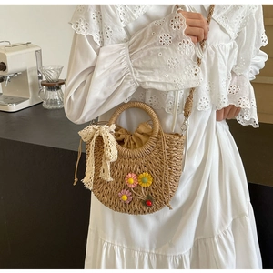 Detail of straw woven crossbody bag with lace bow and floral handmade decorations